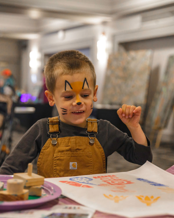Child with painted face doing crafts